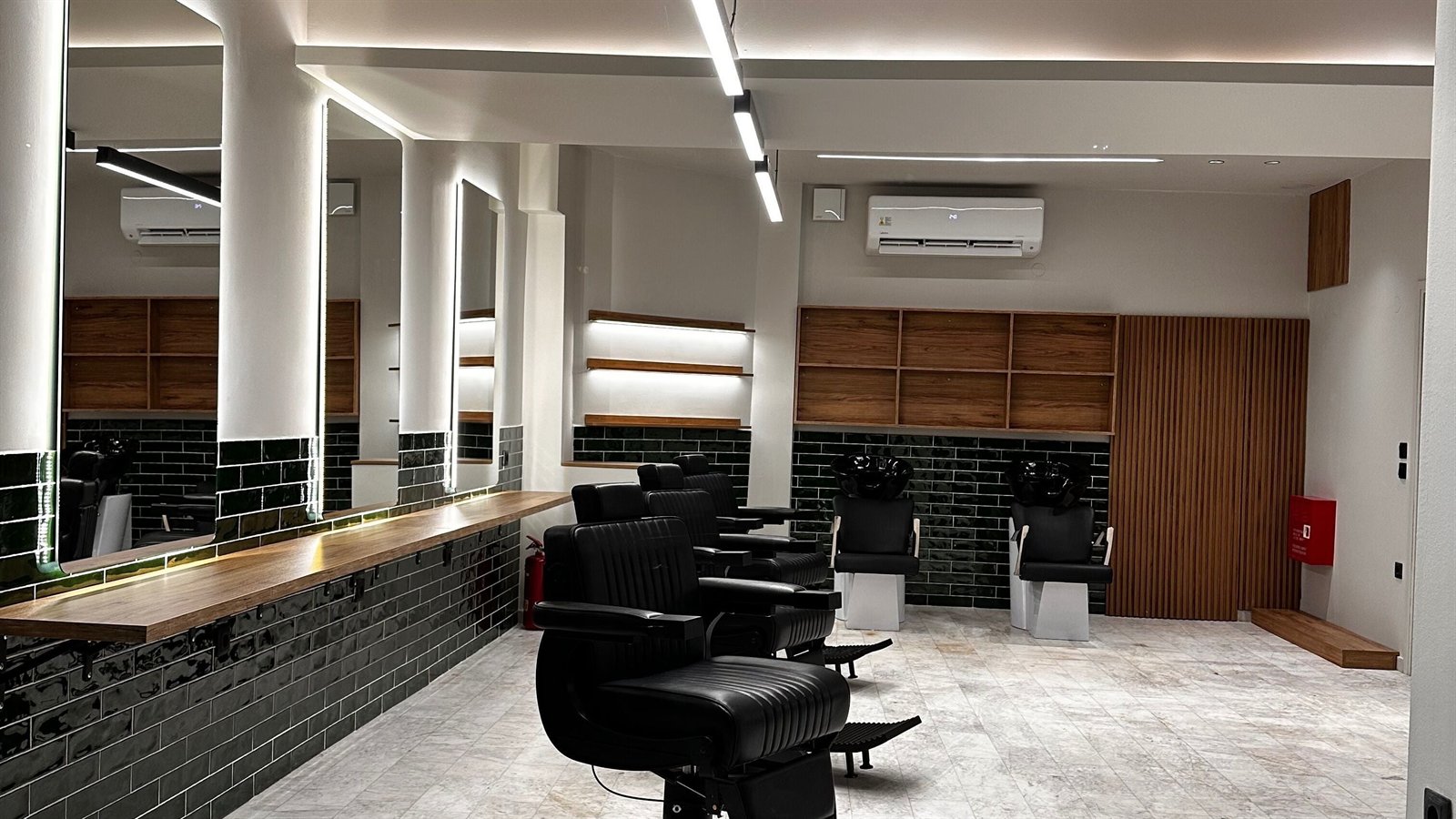 Το εσωτερικό του Hair.stellar με τις μαύρες δερμάτινες καρέκλες και τον ξύλινο πάγκο